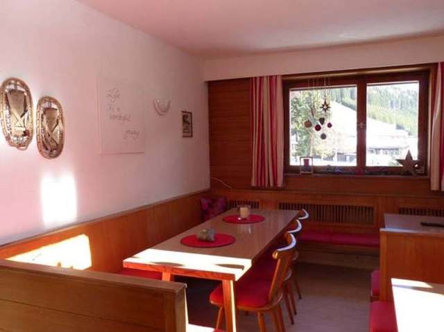 Gemütliche Sitzecke mit Holztisch und rotem Polster