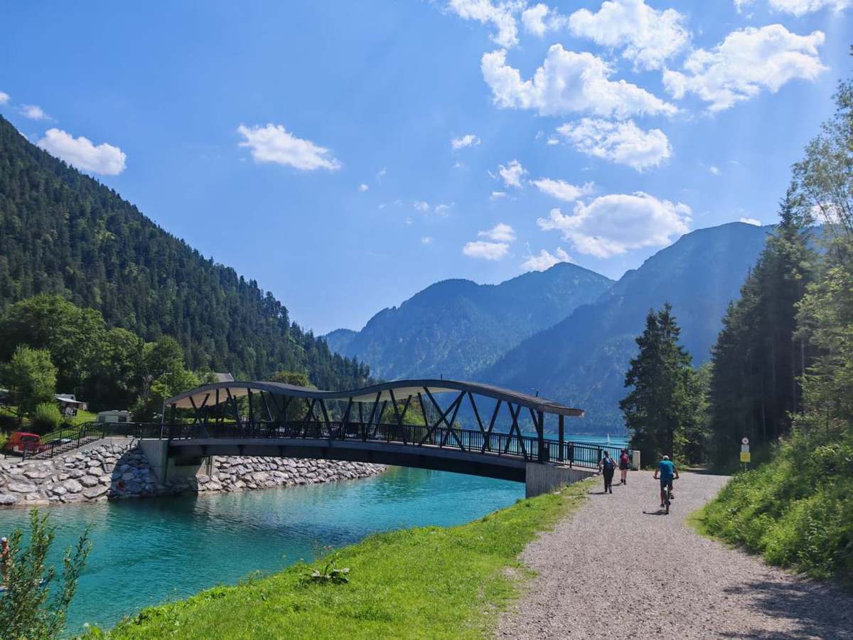 Brücke über türkisblaues Wasser mit Wanderern und Radfahrer
